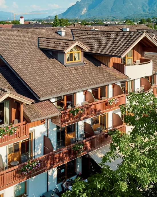 Hotel alpino tradizionale con balconi fioriti e vista sulle montagne in estate