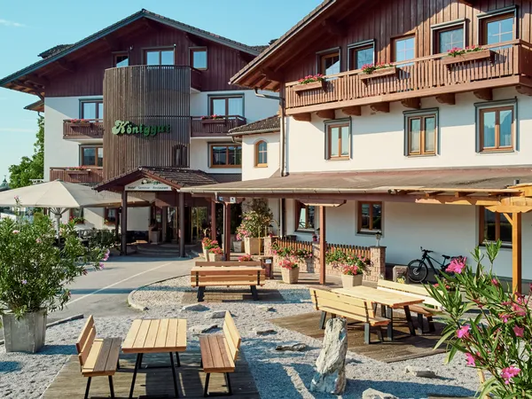 Traditionelles Alpenhotel mit Holzbalkonen, Sitzbereich im Freien und blühenden Pflanzen