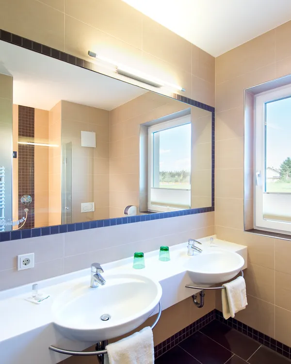 Modernes Badezimmer mit Doppelwaschbecken, großem Spiegel, Fenster mit Ausblick und gefalteten Handtüchern