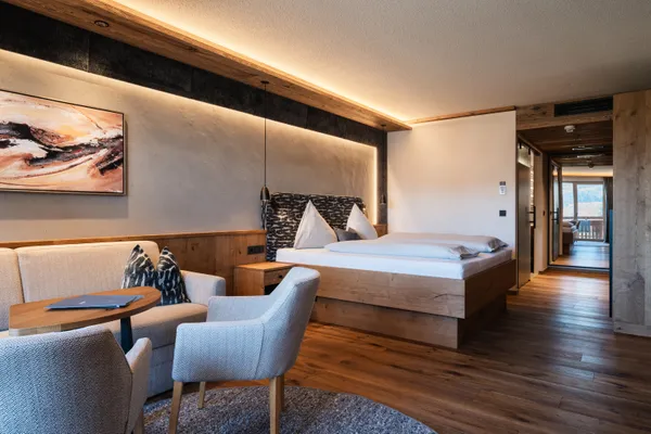 Modernes Hotelzimmer mit Holzmöbeln, Doppelbett und gemütlicher Sitzecke