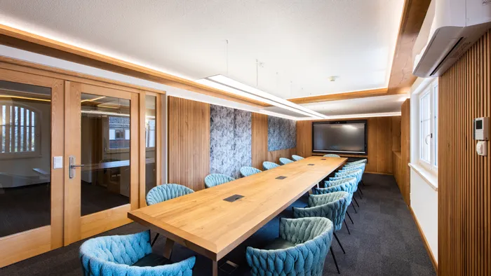 Modern conference room with long wooden table, blue chairs and large screen