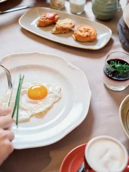 Frühstückstisch mit Spiegelei, Gebäck, Brötchen, Kaffee und frischen Gurkenscheiben