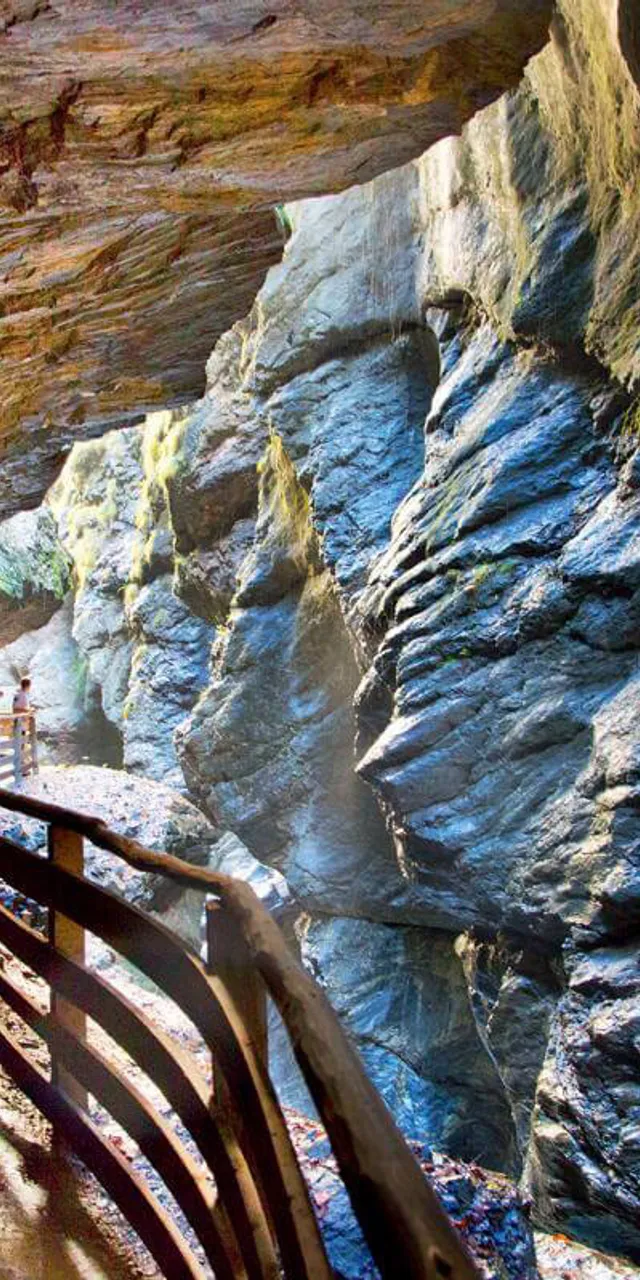 Holzsteg durch eine enge felsige Schlucht mit sonnenbeschienenen Steinwänden